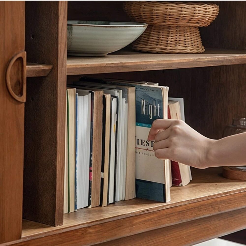 hand_pulling_book_from_teak_sideboard_storage_shelf.jpg Hand pulling book from a