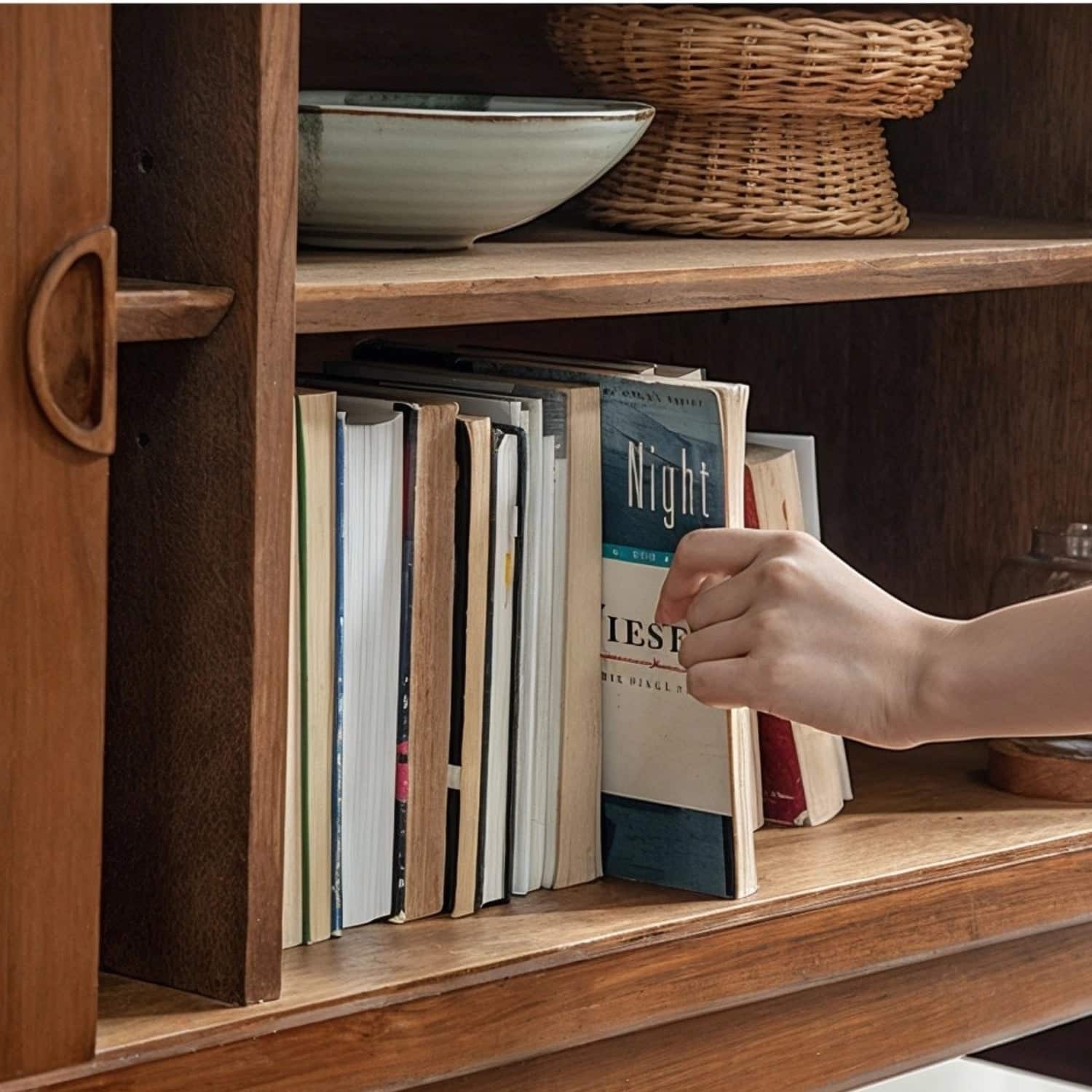 hand_pulling_book_from_teak_sideboard_storage_shelf.jpg Hand pulling book from a