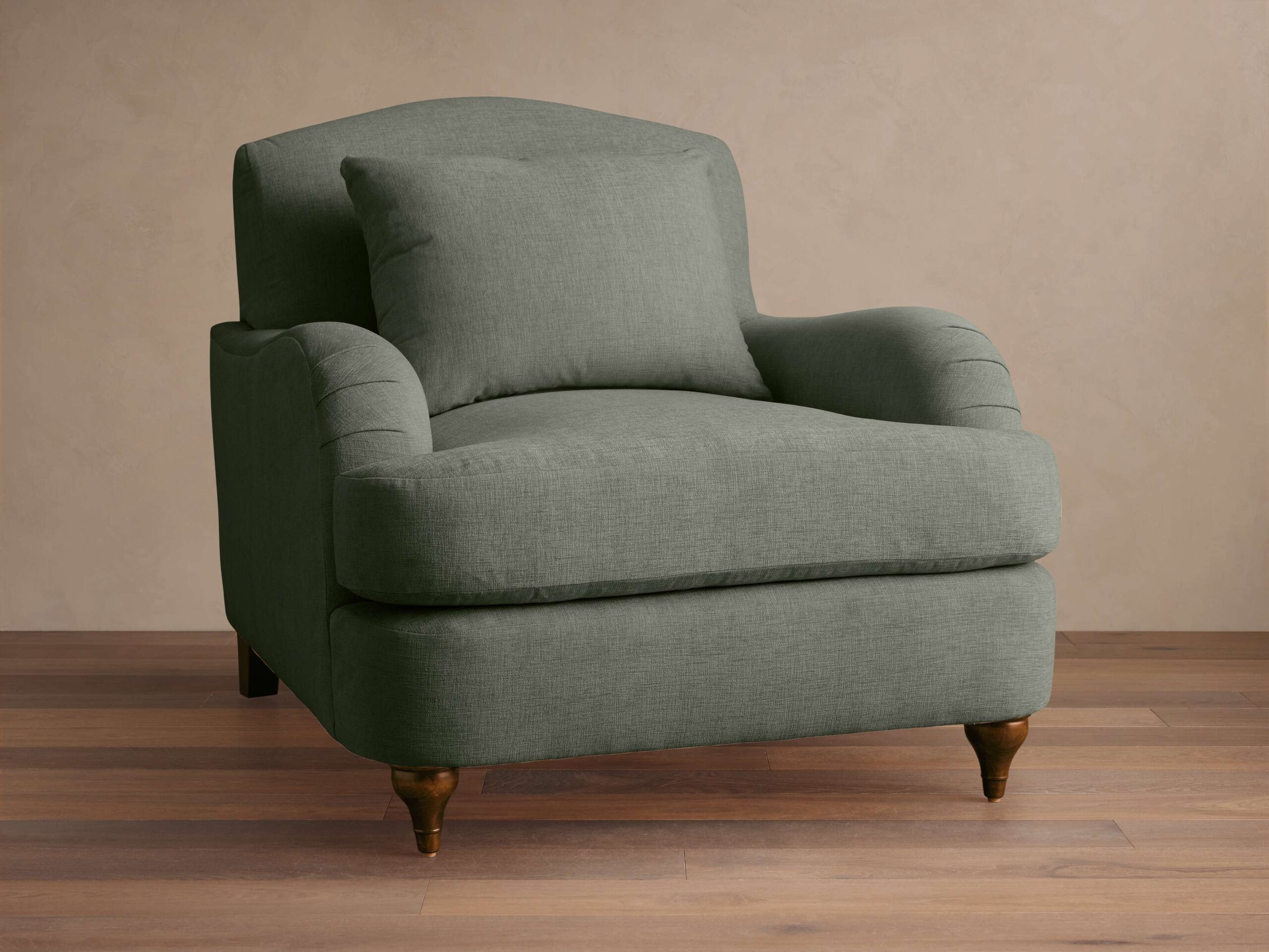 Ormau traditional sage green fabric club chair with a matching lumbar pillow and turned wooden legs.