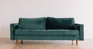 Ormau mid-century modern emerald green velvet sofa with bolster pillows and tapered wooden legs.